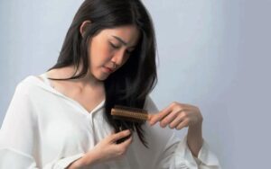 Женщина осматривает кончики тёмных волос