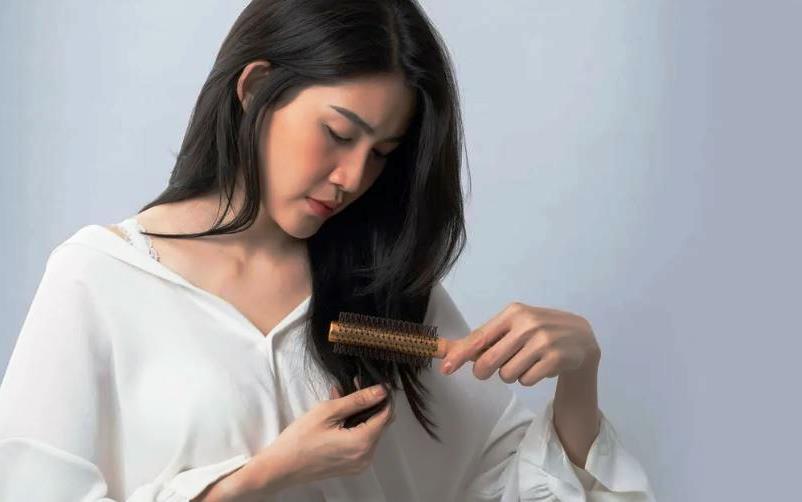 Женщина осматривает кончики тёмных волос