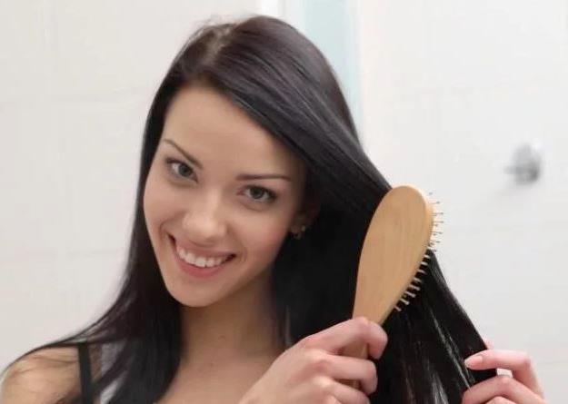 Девушка расчёсывает тёмные волосы деревянной расчёской