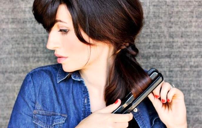 Женщина использует утюжок для стайлинга тёмных волос