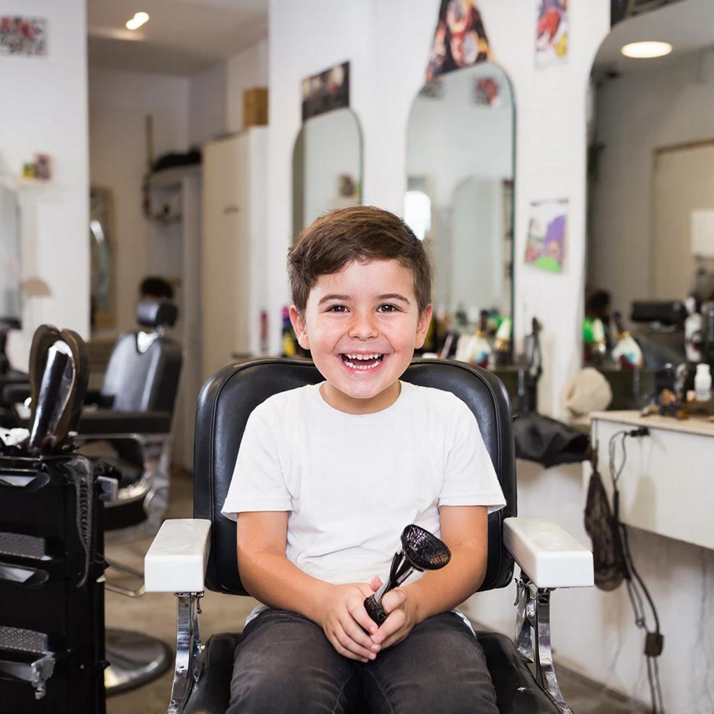 Ребёнок улыбается во время стрижки в парикмахерской