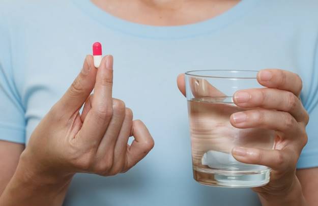 Женщина принимает пробиотики во время восстановления после антибиотиков