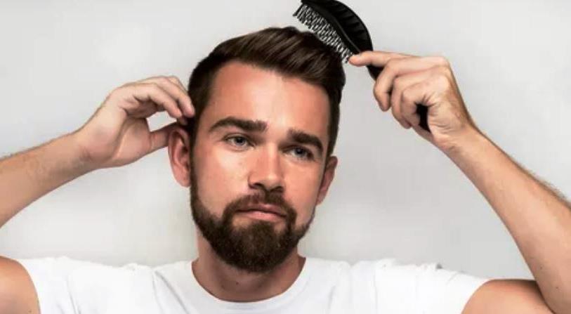 Мужчина причесывает короткие волосы щеткой