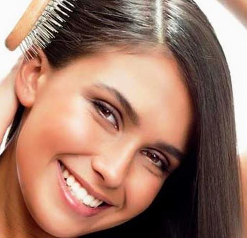 Девушка расчёсывает блестящие гладкие волосы